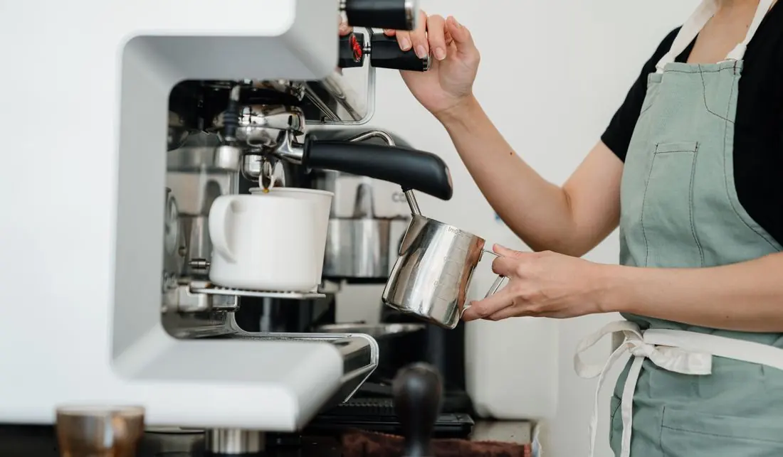 Barista vaporizando leite na máquina de espresso