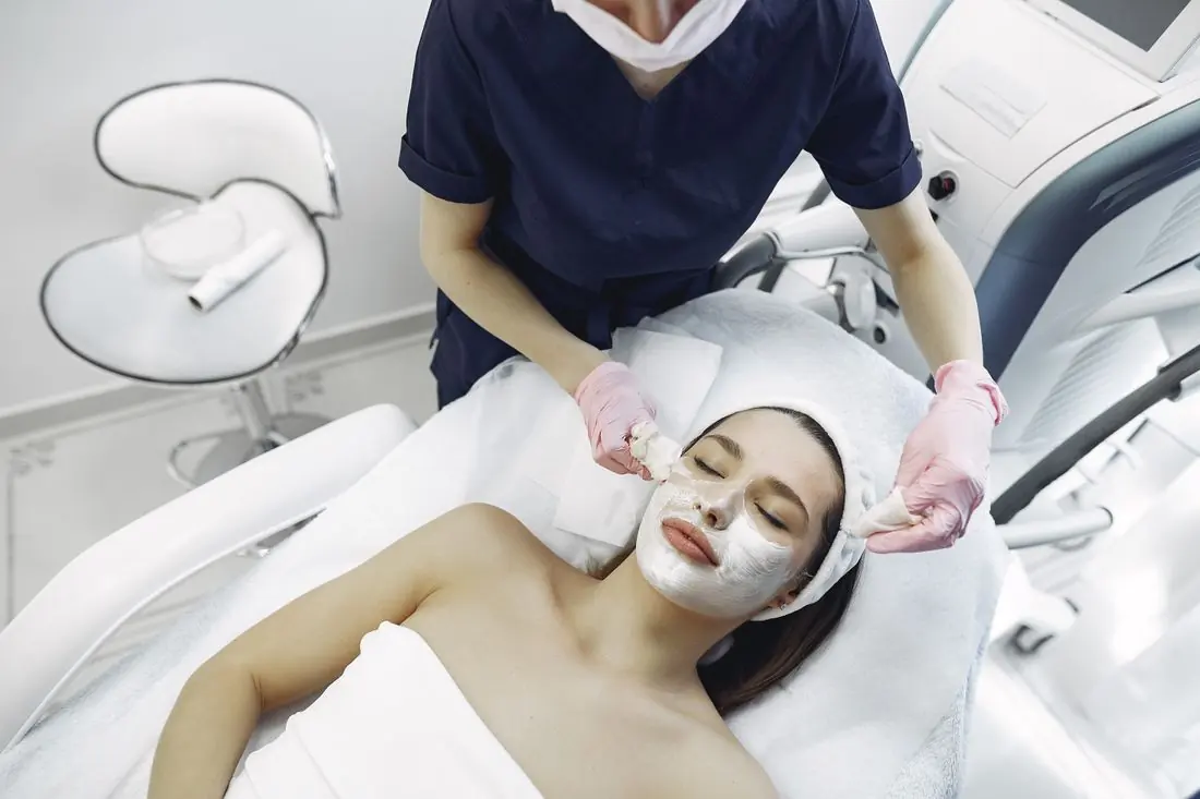 Esteticista aplicando máscara facial