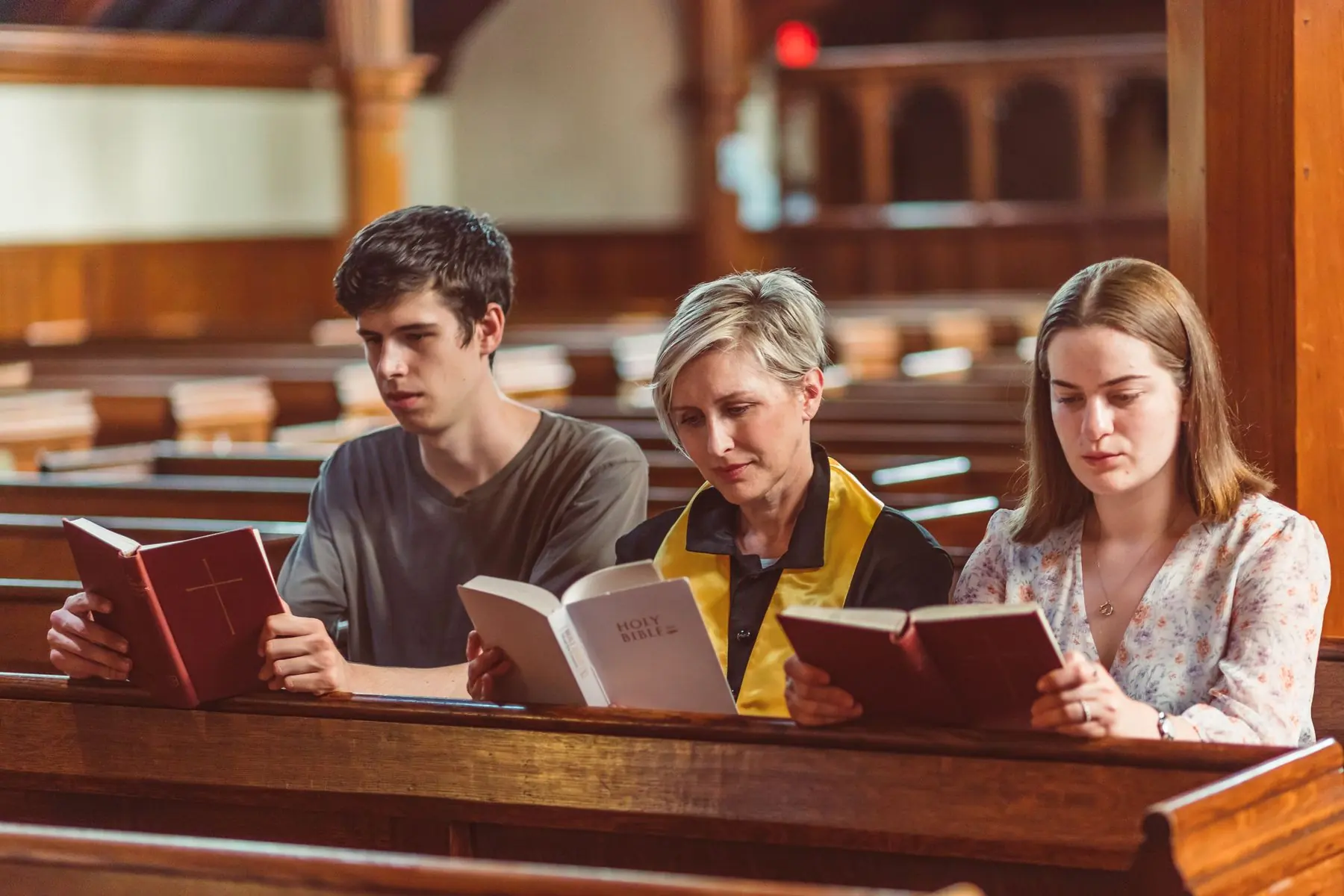 Pessoas lendo a Bíblia nos bancos da igreja
